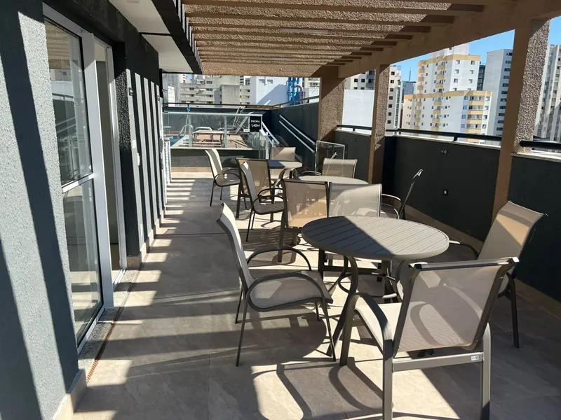 Espaço gourmet entregue no terraço, com pérgola e mesas